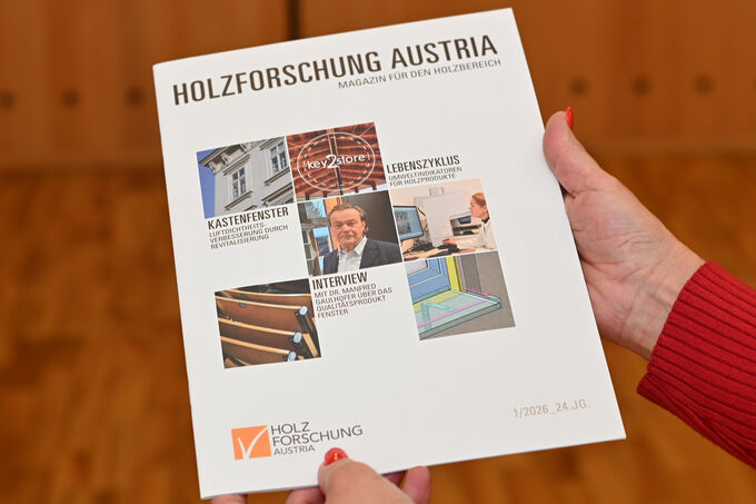 Eine Leserin hält das Magazin für den Holzbereich der Holzforschung Austria in die Kamera.