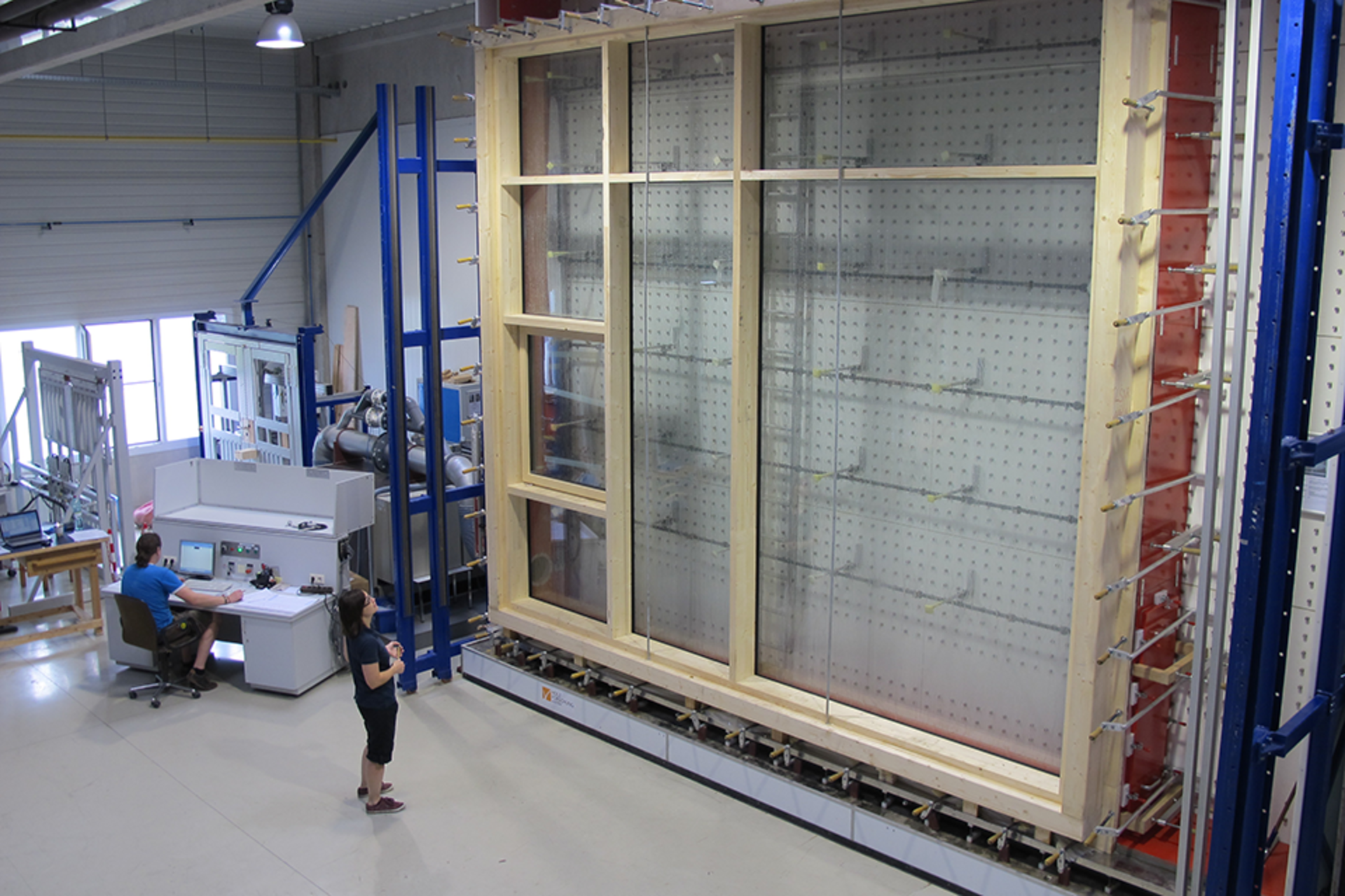 An employee examines a huge glass façade element in the façade test stand at Holzforschung Austria.