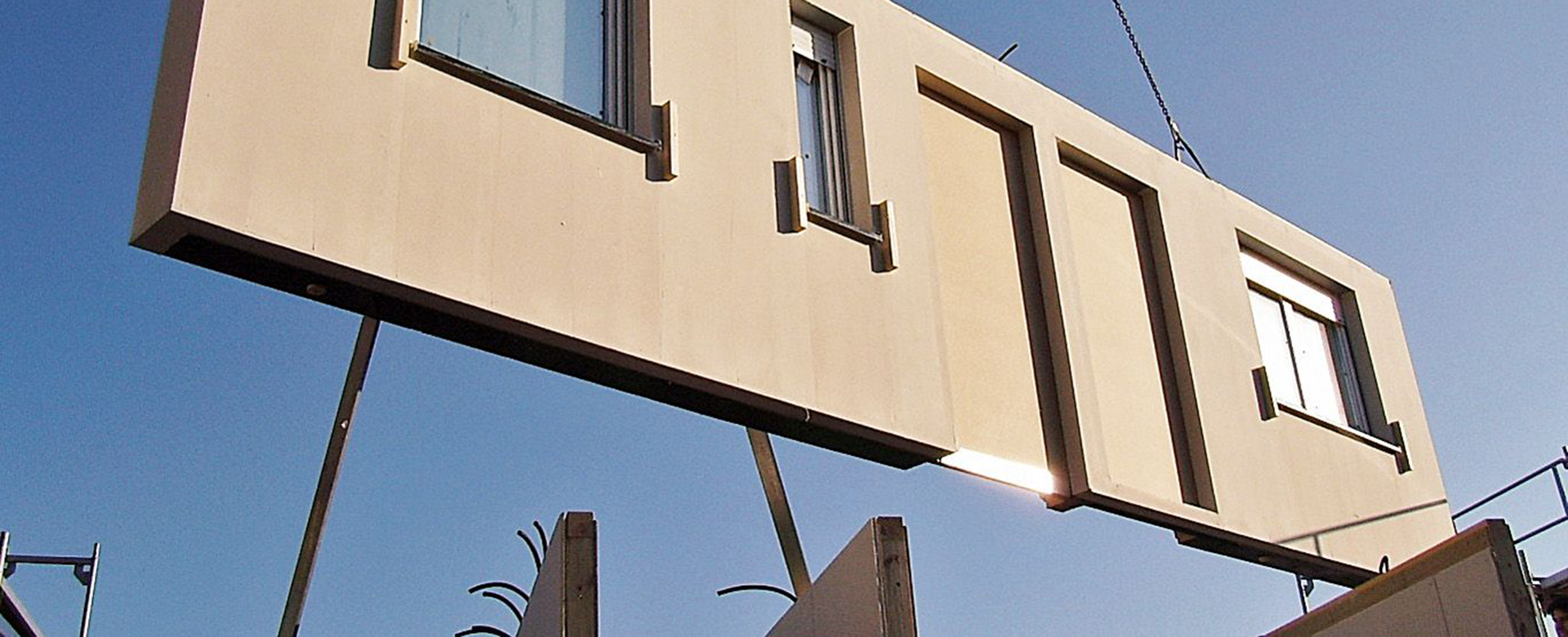 Vorgefertigtes Wandelement wird mittels Kran eingesetzt. Im Hintergrund sieht man den Himmel.