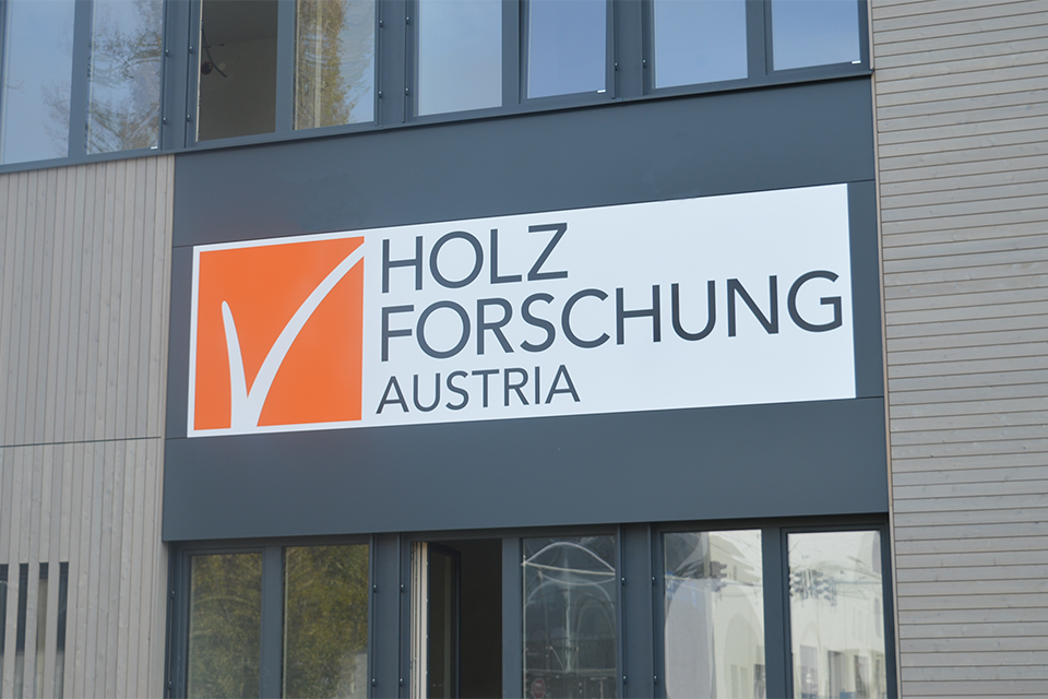 Logo der Holzforschung Austria an der Holzfassade des Zubaus am Standort Arsenal.