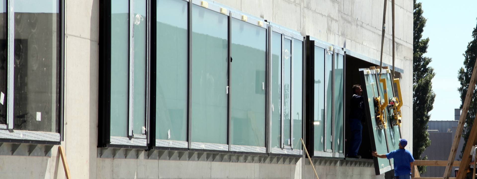 A window is inserted into the window front of a concrete shell using a crane.