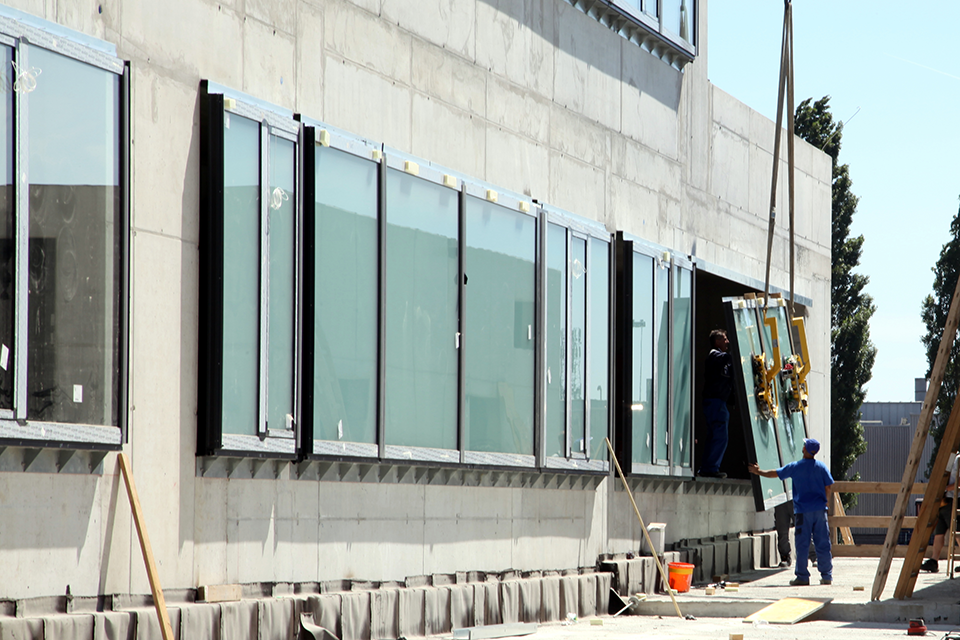 A window is inserted into the window front of a concrete shell using a crane.