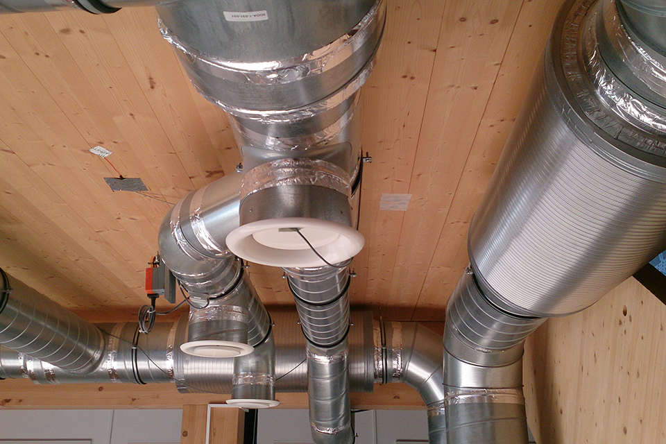 View towards a wooden ceiling on which the pipes for the technical building equipment are mounted.
