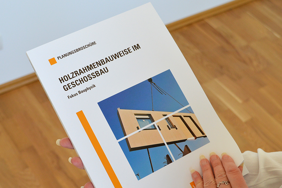 A customer leafs through the specialist brochure Building with cross-laminated timber.